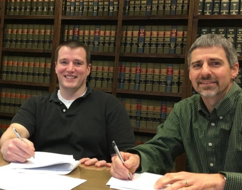 two men sitting at a table in a library